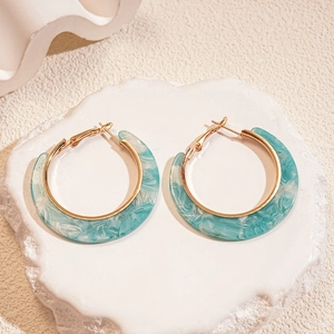 Detailed close-up of C-shaped blue marble acetate resin earrings with gold metal accents
