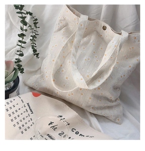 Detail of white daisy canvas tote bag with vintage metal button closure and fabric texture