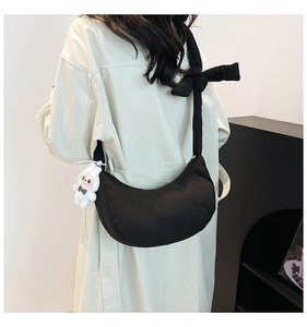 Detail of black dumpling bag with adjustable knotted strap and white bunny charm pendant