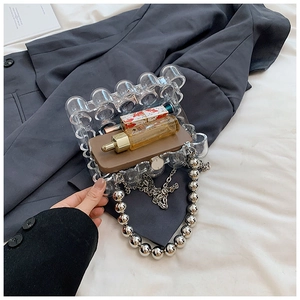 Detailed view of clear acrylic evening bag showing pearl handle and interior capacity