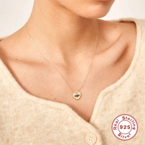 Elegant S925 sterling silver evil eye heart necklace worn on a model with white knitwear