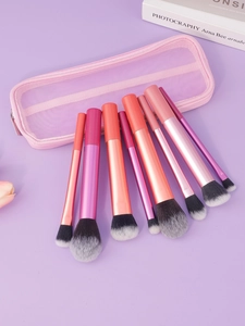 Détail de 8 pinceaux de maquillage avec manches dégradés roses et trousse en filet