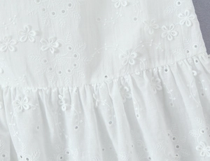 Détail de la broderie florale blanche et bordure volantée sur tissu en coton et lin
