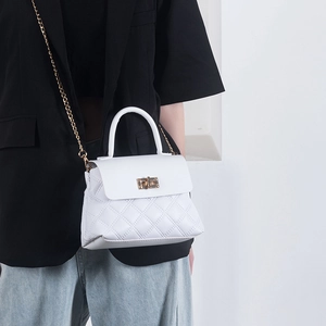 White quilted flap handbag with gold chain strap and top handle on a stylish model