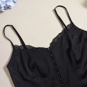 Detail of adjustable straps and delicate lace trim on this black camisole top