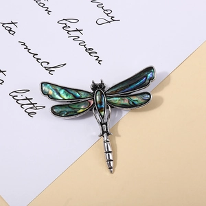 Dettaglio di una spilla a libellula con guscio di abalone iridescente e base in argento