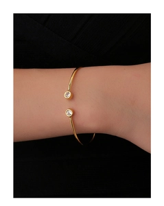 Close-up of gold open cuff bracelet featuring sparkling round zircon stones on a model