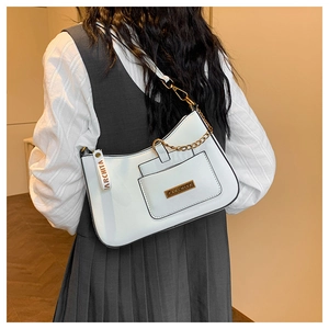 Close-up of white crossbody bag featuring a gold chain strap and metal logo plaque
