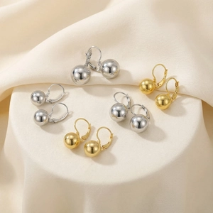 Detailed set of gold and silver lever-back ball drop earrings on soft textured fabric