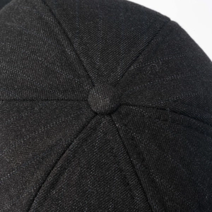 Macro view of black winter baseball cap top button and detailed reinforced stitching