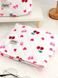 Quilted white cosmetic bag with red cherry patterns and elegant pink zipper detail