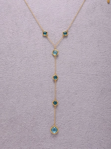 Dettaglio della collana a Y placcata oro 18k con pietre di vetro blu su velluto