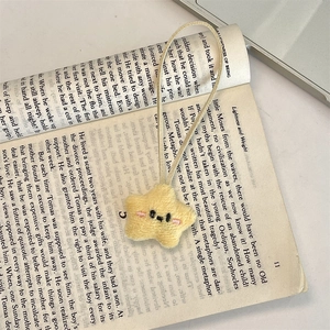 Close-up of a cute yellow plush star charm with embroidered face on an open book