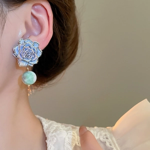 Close-up of vintage flower earrings with blue roses and green spherical drop charms