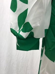 Detail of lantern sleeve cuff featuring vibrant green leaf print on white chiffon dress