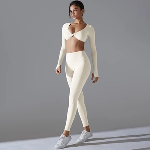 Detail eines cremefarbenen Yoga-Sets mit geknotetem V-Ausschnitt-Top und Daumenlochbündchen