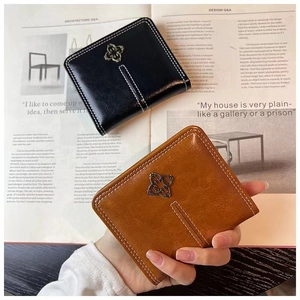 Detail view of mini PU leather wallets in black and brown with clover metal badge