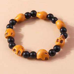 Halloween beaded bracelet featuring black round beads and brownish skull charms on beige background