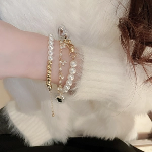Detailed view of 3-piece layered bracelet set with gold chains, pearls, and heart charm
