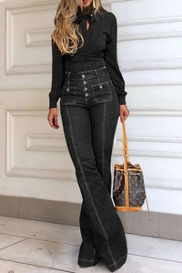 Detail showing the high-waist row of buttons and flared hem of the washed denim jeans