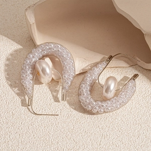 Detailed view of U-shaped mesh earrings with faux pearl on elegant stone background