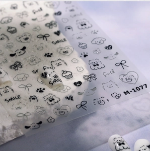 Close-up of M-1077 nail decals featuring black line art of cute puppies and kittens
