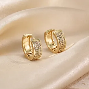 Macro view of gold huggie earrings with pavé cubic zirconia on champagne silk