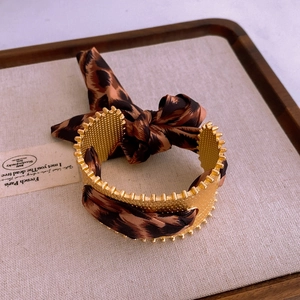 Detail eines Vintage Goldarmbands mit Leopardenmuster Seidenschal Schleife Design