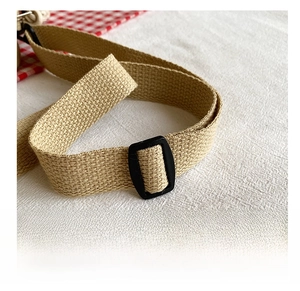 Detail of adjustable beige woven strap with black plastic buckle for small crossbody bags