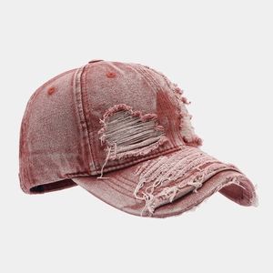 Detail of vintage washed rust red baseball cap featuring heart-shaped distressed holes