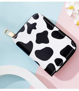 Macro shot of cow print zipper card holder with gold hardware on a bicolor backdrop