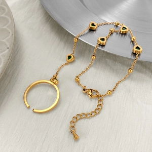 Detailed close-up of gold hand chain with green heart gemstones and adjustable ring band
