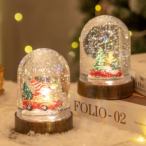 Christmas snow globe with red truck, Santa and tree on dark wood base with bokeh lights