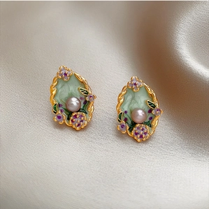 Macro detail of French style gold flower earring with green enamel and center pearl