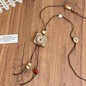 Dettaglio della collana bohémien in perline di legno con ciondolo a fiore su legno