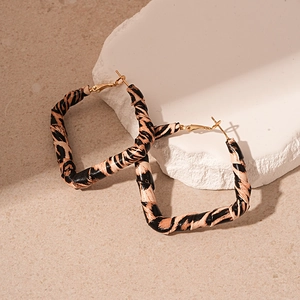 Detail of square leopard print earrings with faux leather texture on stone props