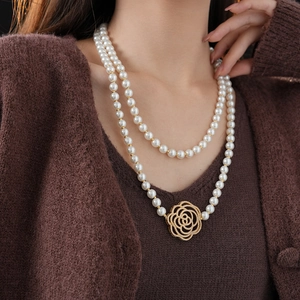 Close-up of double-layer pearl necklace with a hollow gold rose pendant and zircon details