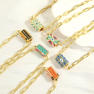 Detailed macro view of a gold-plated paperclip chain with a colorful evil eye Amour pendant