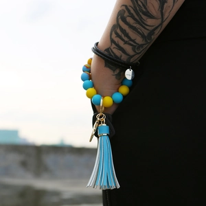 Close-up of silicone beaded wristlet keychain with blue tassel and gold ring detail