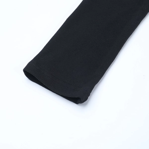 Gros plan sur les coutures délicates et la texture du tricot noir au poignet de la robe