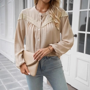 Detail of elegant beige long sleeve blouse showing lace patchwork and fabric texture