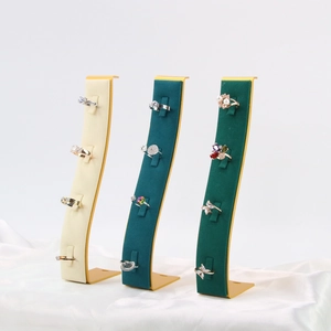 Three curved velvet jewelry stands showcasing assorted rings on elegant white silk fabric