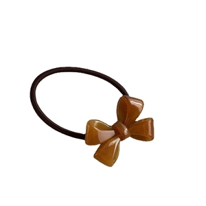 Elegant amber acrylic bow hair tie with dark brown elastic band on white background