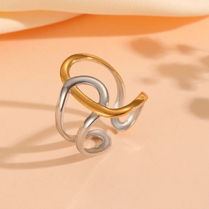 Close-up of wavy gold and silver interlaced stainless steel ring on pink satin fabric