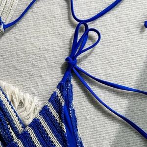 Close-up of blue and white crochet bikini set featuring lace-up ties and bohemian fringe
