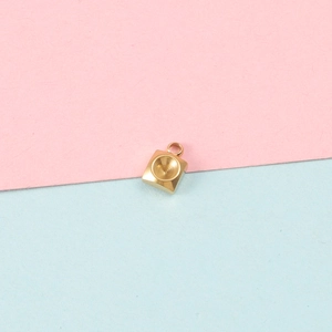 Macro view of a gold square stainless steel pendant with round bezel on a pink background