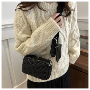 Detail of black quilted shoulder bag featuring wide strap and detachable mini coin pouch