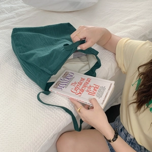 Detail of dark green canvas tote bag with thick texture on a cozy white bed