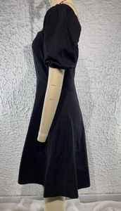 Side view of black square neck dress featuring puff sleeves and an A-line skirt