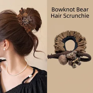 Detail view of a brown velvet scrunchie with leopard pattern bear and plush ball